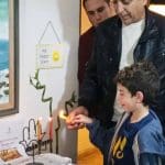 נר_ראשון_בבית_משפחת_אפרת_בחיפה._צילום_-_יעל_אפרת__החוגגת_עם_12_נכדיה_את_הדלקת_הנר_הראשון