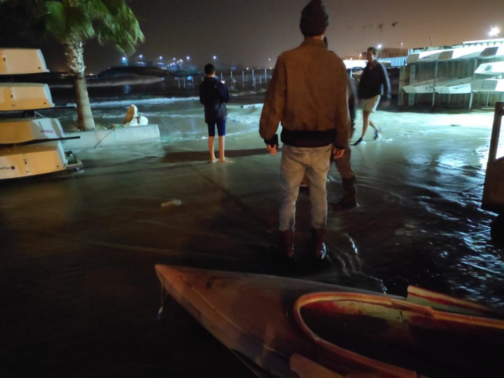 מתנדבים מצילים את הציוד כאשר גלי הענק מציפים את המועדון בחוף השקט בחיפה וסוחפים את הסירות למים (צילום: אילן אליהו)