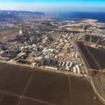 מתחם קרקעות הצפון (השטח החום בתחתית התמונה) ממזרח לקיר בתי הזיקוק ומתקן כרמל אולפינים ברקע – הכרמל והעיר חיפה (צילום: חי פה)
