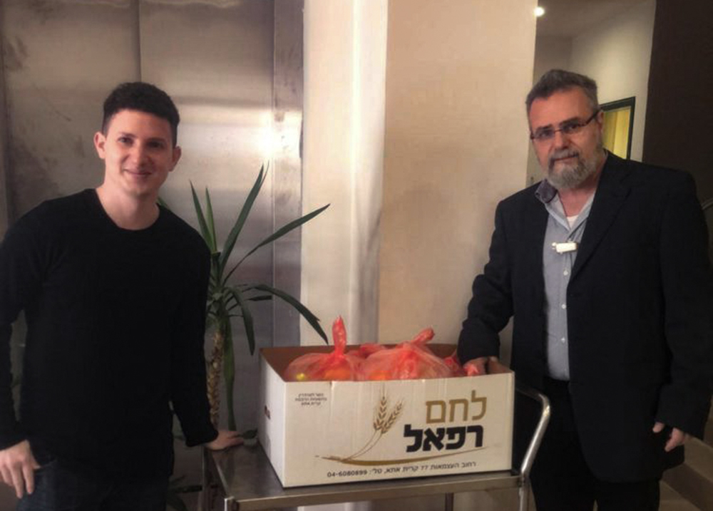 הרב דב חיון סגן ראש העיר חיפה עם עוזרו ארנון בחלקת מזון לקשישים (צילום: מירב אסידו)