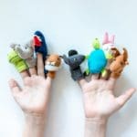 Hands of a child with finger puppets, toys, dolls close up on white background – playing puppet theatre and children entertainment concept
