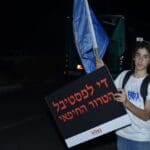 מפגין הנושא שלט בהפקת "בצלמו"  (צילום: חגית אברהם)