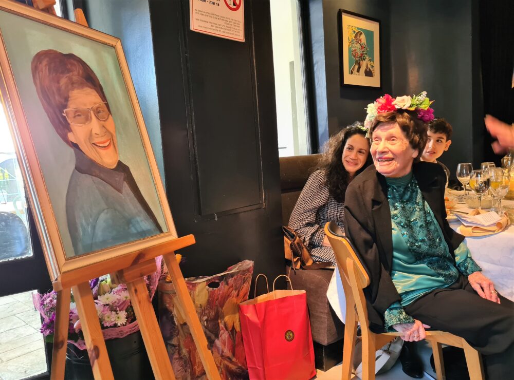 מירה צ'רניאבסקי ביום הולדתה ה-100 מביטה בדיוקנה שצויר ע"י חברתה מילה.
צילום: יעל הורוביץ  