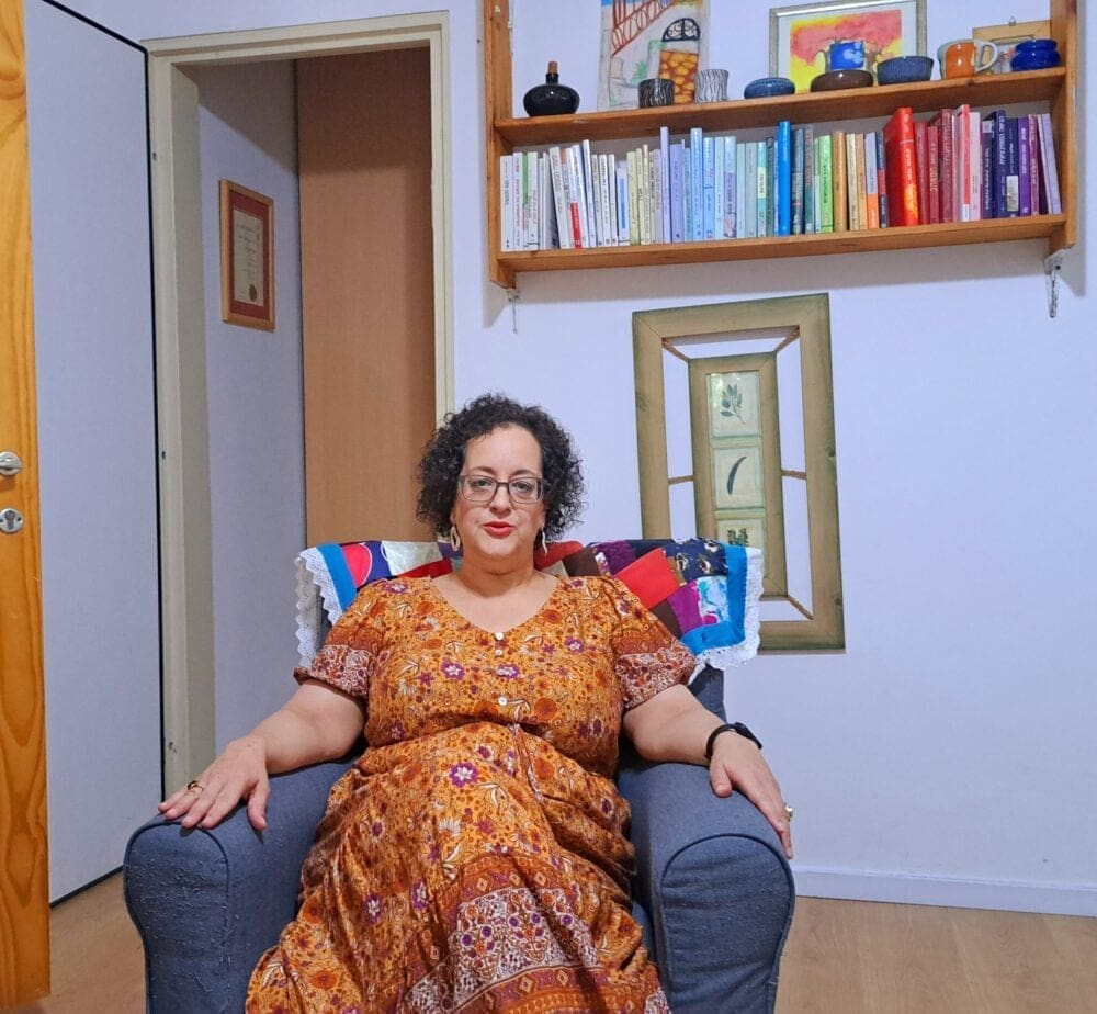 ספרייה נוספת, תמונת ריקמה וכורסת המטפלת- בחדר הקליניקה בבית עו"ס יפעת מזרחי (צילום: רחלי אורבך)