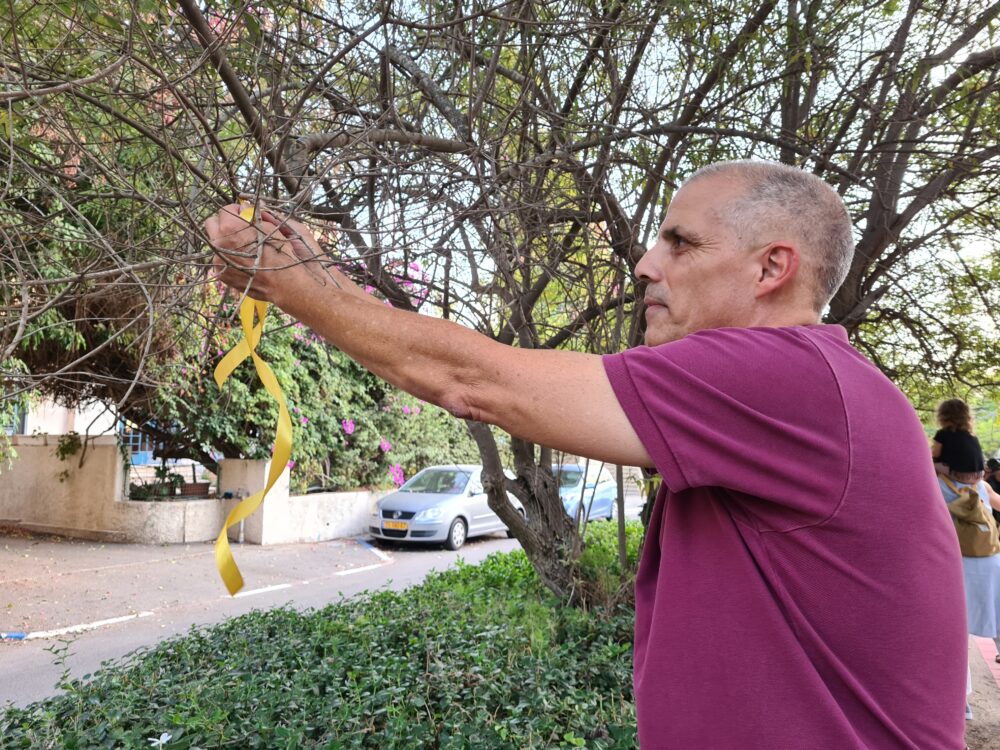 קושרים סרטים צהובים סביב עצים בחיפה כסמל להחזרת החטופים (צילום: יעל הורוביץ)