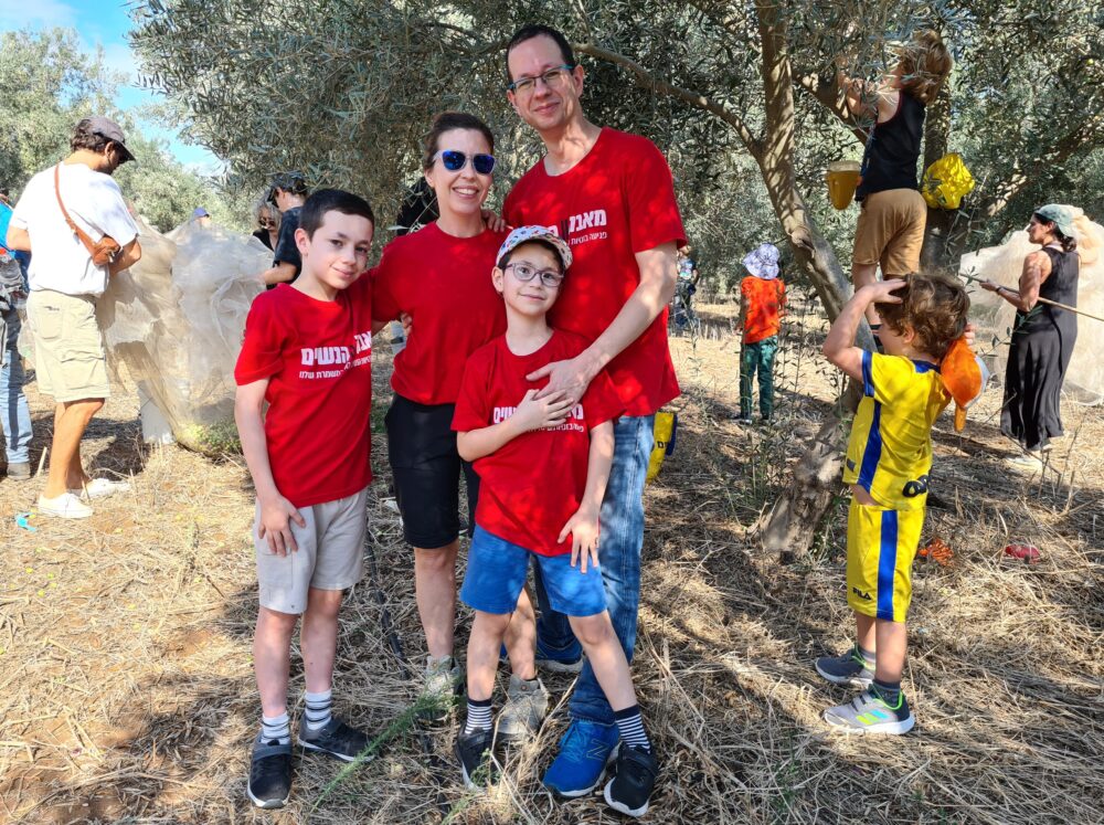 חן מנדלסון אדרקה, מובילת 'בונות אלטרנטיבה' בחיפה, עם משפחתה במסיק הזיתים במטע הסקוטי (צילום: יעל הורוביץ)