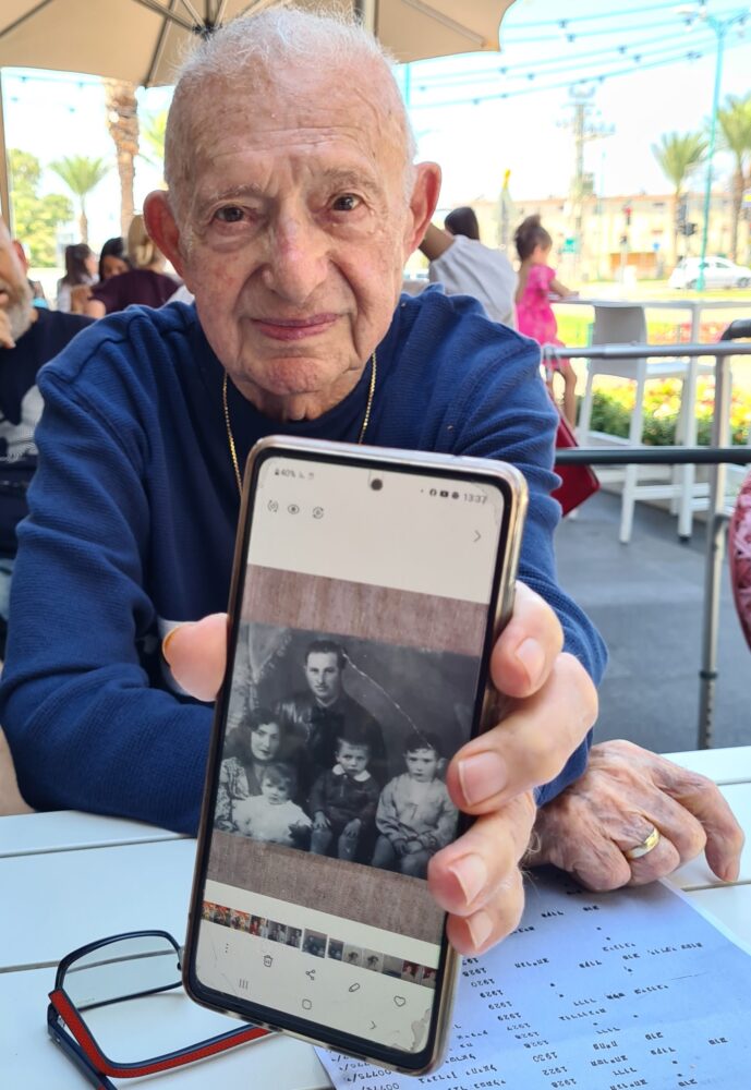 אברהם ארי ותמונת משפחתו שנספתה בשואה (צילום: יעל הורוביץ) 