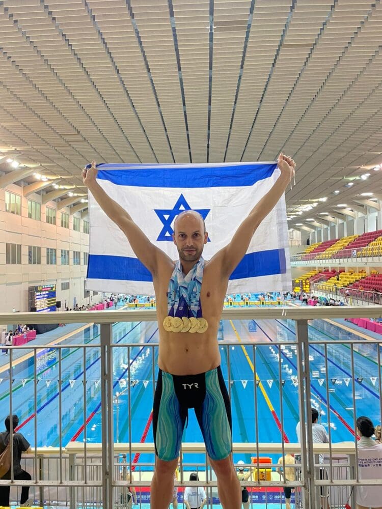 דניאל קציר עם המדליות ודגל ישראל על רקע הבריכה (אלבום פרטי)