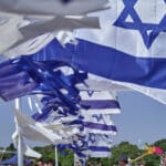 דגלי ישראל מתנופפים ברוח וערימות חציר בחגיגת שבועות בקיבוץ (צילום: שרון לייבל)