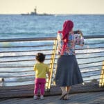 אישה וילדה בטיילת שקמונה כשברקע ספינת טילים (צילום: שרון לייבל)