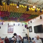 סוכת בית בשכונת השומרונים, חולון – סוכה תלויה מן התקרה, צבעונית, זוהרת ועמוסת פירות (צילום: רחלי אורבך)