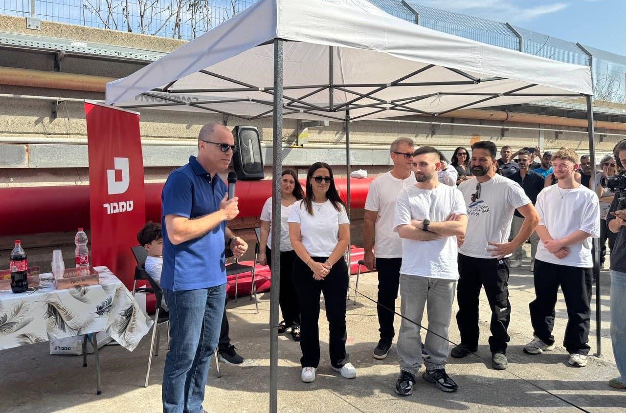 מתן אנגרסט מסיר את השלט שקרא לשחרורו ממפעל טמבור בעכו (צילום: טמבור)