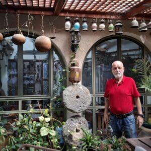 משה צמרת – בחצרו: צמחייה ירוקה, אבני ריחיים ופרטים נוספים (צילום: רחלי אורבך)