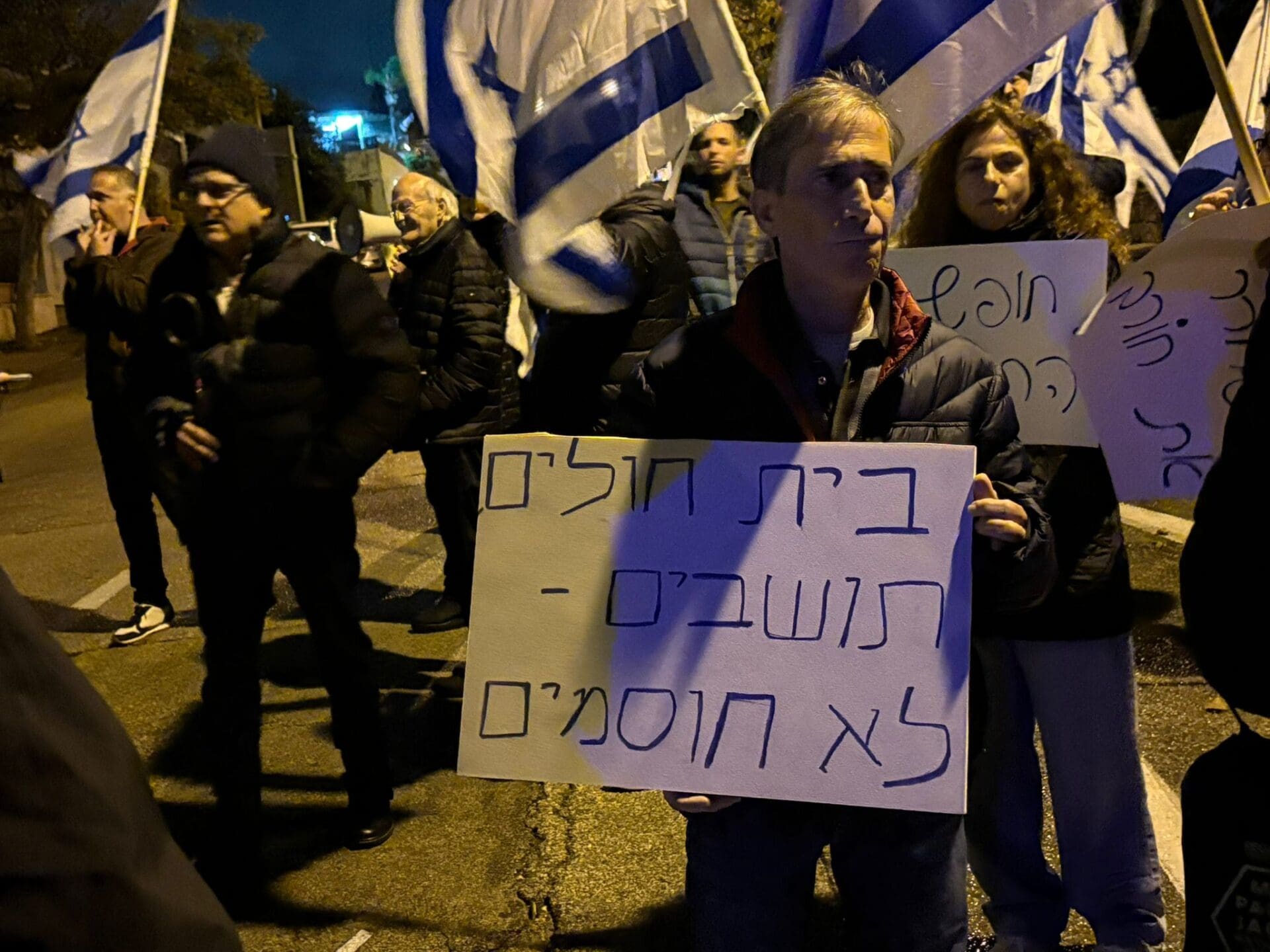 מפגינים עם שלט נגד חסימת המרכז הרפואי כרמל (צילום: מיכל גרובר)