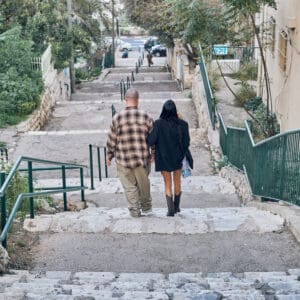 זוג, מדרגות עירוניות, חיפה, שכונת הדר, רחוב מדורג, ירידה במדרגות, מרחב ציבורי, סביבה עירונית, מדרגות אבן, מעקה מתכת ירוק, הליכה משותפת, צילום רחוב, זוג מאחור, שביל רגלי, בנייני מגורים ישנים, צמחייה עירונית, שכונה ותיקה, אינטימיות יומיומית, תיעוד עירוני, חיים בעיר,  מדרגות שוקרי חיפה, שכונת הדר, מדרגות עירוניות, רחוב מדורג, שביל רגלי, מדרגות אבן, מעקה מתכת ירוק, חיבור בין רחובות, טופוגרפיה הררית, מרחב ציבורי, מעבר הולכי רגל, בנייני מגורים ותיקים, צמחייה עירונית, סמטאות חיפה, צילום רחוב, תיעוד עירוני, נוף שכונתי, תנועה יומיומית, אדריכלות מקומית, מדרון