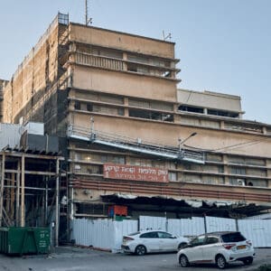 שוק תלפיות חיפה, מבנה באוהאוס, אדריכלות מודרניסטית, מבנה מעוגל, שימור מבנים, שוק עירוני, שכונת הדר, מבנה היסטורי, חזית בטון, חלונות סרט, מבנה נטוש, תשתיות חשופות, צנרת חיצונית, גדר מתכת, קיר בטון, התחדשות עירונית, מורשת אדריכלית, מבנה ציבורי, סגנון בינלאומי,  אדריכלות