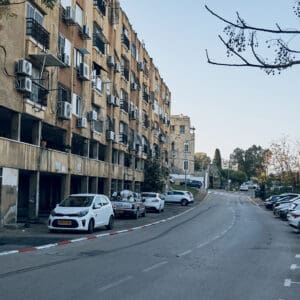 ואדי סליב, סאליב, בניין מגורים, שיכון ישן, חזית בטון, בנייה רוויה, שכונת מגורים, בניין דירות, מזגנים חיצוניים, מרפסות סגורות, תריסים, סורגים לחלונות, קירות מתקלפים, תשתיות חשופות, עמודי תמך, קומת עמודים, חניה פתוחה, רחוב עירוני, עץ בשלכת, שמיים מעוננים, אדריכלות ישראלית ישנה, צפיפות עירונית, נפתלי אימבר, שוק תלפיות, נפתלי הרץ אימבר, הדר