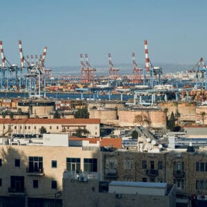 נמל חיפה, מנופי נמל, עגורני גשר, מסופי מכולות, מכולות מטען, לוגיסטיקה ימית, תשתיות נמל, פעילות מסחרית, ספנות בינלאומית, מפרץ חיפה, מיכלי דלק פז, מכלי אחסון נפט, תעשייה פטרוכימית, אזור תעשייה, קווי הולכה, רכבת משא, מסילת רכבת, קו חוף, נוף עירוני תעשייתי
