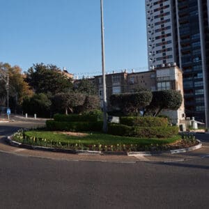 פינוי בינוי, התחדשות עירונית, תמ״א 38, הריסה ובנייה מחדש, חיזוק מבנים, שדרוג תשתיות, בנייה רוויה, צפיפות עירונית, תכנון עירוני, מדיניות דיור, התחדשות שכונות ותיקות, פיתוח עירוני, שינוי ייעוד קרקע, הגדלת זכויות בנייה, שימור מול פיתוח, חידוש חזיתות, שיפור איכות חיים, השקעות נדל״ן, עליית ערך נכסים, פרויקטים למגורים, שיתוף דיירים, פיצוי דיירים, יזמות נדל״ן, רגולציה תכנונית, היתרי בנייה, ועדות תכנון ובנייה, שיקום מבנים ישנים, התחדשות תשתיות עירוניות, התחדשות מרכזי ערים, בנייה לגובה, בניין מגורים ישן, שיכון, בלוק דירות, חזית בניין, ארכיטקטורה ישראלית, שכונת מגורים, עיר ישראלית, רחוב עירוני, תחנת אוטובוס, תחבורה ציבורית, תחנת המתנה, עץ אורן, צמחייה עירונית, מדרכה, אבני סלע, כביש רטוב, שמש חזקה, שמיים כחולים, אור וצל, חזית מוזנחת, תריסים סגורים, מזגנים חיצוניים, אנטנות על הגג, צילום רחוב, סביבה עירונית, דיור ציבורי, מבנה בטון, שכונה ותיקה, נוף עירוני, כיכר