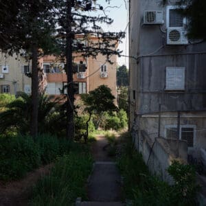 פינוי בינוי, התחדשות עירונית, תמ״א 38, הריסה ובנייה מחדש, חיזוק מבנים, שדרוג תשתיות, בנייה רוויה, צפיפות עירונית, תכנון עירוני, מדיניות דיור, התחדשות שכונות ותיקות, פיתוח עירוני, שינוי ייעוד קרקע, הגדלת זכויות בנייה, שימור מול פיתוח, חידוש חזיתות, שיפור איכות חיים, השקעות נדל״ן, עליית ערך נכסים, פרויקטים למגורים, שיתוף דיירים, פיצוי דיירים, יזמות נדל״ן, רגולציה תכנונית, היתרי בנייה, ועדות תכנון ובנייה, שיקום מבנים ישנים, התחדשות תשתיות עירוניות, התחדשות מרכזי ערים, בנייה לגובה, בניין מגורים ישן, שיכון, בלוק דירות, חזית בניין, ארכיטקטורה ישראלית, שכונת מגורים, עיר ישראלית, רחוב עירוני, תחנת אוטובוס, תחבורה ציבורית, תחנת המתנה, עץ אורן, צמחייה עירונית, מדרכה, אבני סלע, כביש רטוב, שמש חזקה, שמיים כחולים, אור וצל, חזית מוזנחת, תריסים סגורים, מזגנים חיצוניים, אנטנות על הגג, צילום רחוב, סביבה עירונית, דיור ציבורי, מבנה בטון, שכונה ותיקה, נוף עירוני