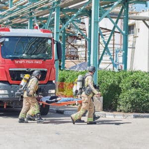 חילוץ, כיבוי, כבאים, כבאות, הצלה, חירום, פצוע, אלונקה, ספינה, כימיקלים, נמל, חיפה, ישראל, תעשייה, מפעל, אסון, סכנה, איום, מלחמה, טילים, פגיעה, תקיפה, משבר, תגובה, צוות, כבאי, לוחם, מדים, קסדה, מסכה, נשימה, בלון, דרגר, ציוד, רתמה, חבלים, קרבינה, מנוף, הרמה, גובה, טיפוס, פינוי, נשיאה, טיפול, עזרה, פצועים, מטופל, מבצע, משימה, מוכנות, בטיחות, תרגיל, אימון, תיאום, פיקוד, תדריך, מסמך, בדיקה, קשר, תקשורת, מוטורולה, צינור, מים, התזה, קירור, מגדל, סולם, מתקן, צינורות, פלדה, רציף, ים, ספנות, לוגיסטיקה, משאית, כבאית, פעילות, תמיכה, אבטחה, תפעול, כוננות, גיבוי, הדרכה, הכשרה, צוותים