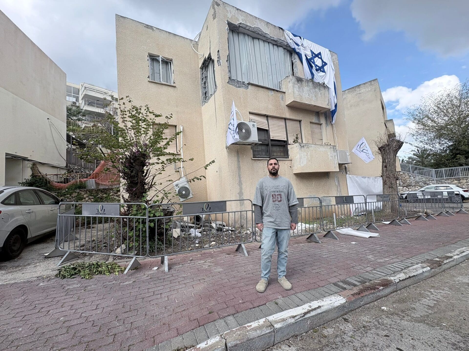 נדב על רקע הבית שנפגע (צילום: מיכל גרובר)