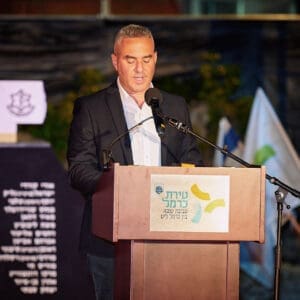 יום זכרון, עצרת, טירת כרמל, דודו כהן, ראש עיר, זיכרון, טקס, ערב, נרות, קהל, הורים, שכולים, אבל, דגל, חללים, חיילים, הנצחה, שידור, הקלטה, במה, נאום, התכנסות, כבוד, שתיקה, דומייה, דגלים