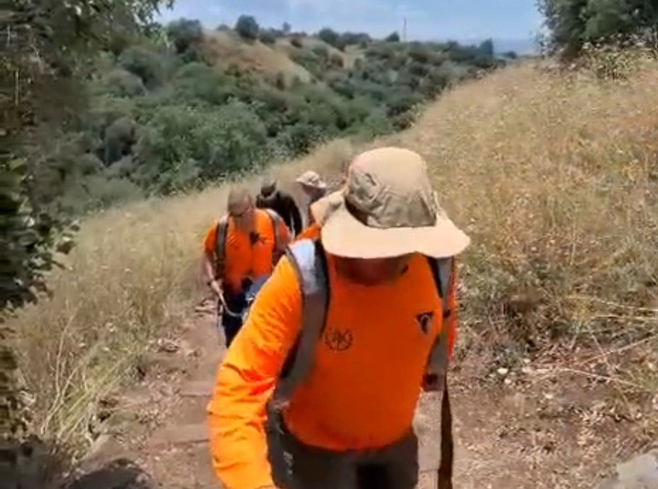 אישה חולצה לאחר שנפגעה ברגלה בשמורת מפל הבניאס - המחלצים נושאים את המחולצת באלונקה במעלה השביל. 23/5/26 (צילום: דוברות משטרת ישראל)