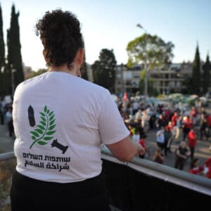 הפגנה, מחאה, שלטים, דגלים, דגל ישראל, נאום, נואם, במה, מיקרופון, קהל, אנשים, רחוב, מבנים, עצים, כיכר, צעדת מחאה, כרזות, פוליטיקה, אקטיביזם, התקהלות, פלסטין, פלסטינים, כיבוש, 1967, עימות