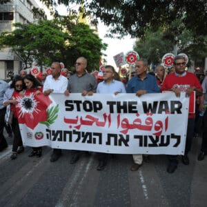 הפגנה, מחאה, שלטים, דגלים, דגל ישראל, נאום, נואם, במה, מיקרופון, קהל, אנשים, רחוב, מבנים, עצים, כיכר, צעדת מחאה, כרזות, פוליטיקה, אקטיביזם, התקהלות, פלסטין, פלסטינים, כיבוש, 1967, עימות