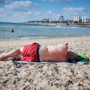 חוף ים, חול, גבר, שיזוף, מנוחה, שכיבה, בגד ים, אדום, גל, מים, שמיים, עננים, קו רקיע, בניינים, עיר, סנדל, מגבת, קיץ, שמש, חופש, נופש, שמש, נזקי שמש, שיזוף, חום, שרב, { "keywords": "שרב, חום, קיץ, שמש, שיזוף, נזקי שמש, קרינה, כוויה, חוף ים, גבר, מנוחה, שכיבה, גב, בגד ים, אדום, חול, ישראל, אקלים, מזג אוויר, חופש, בריאות, נשרף, נכווה, כוויה