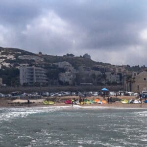 גולשים בחוף הכנסיה ומאחוריהם הענן השחור של הקיץ, המיטיב עם תושבי חיפה כשהוא עושה צל על הכרמל (צילום: ירון כרמי)
