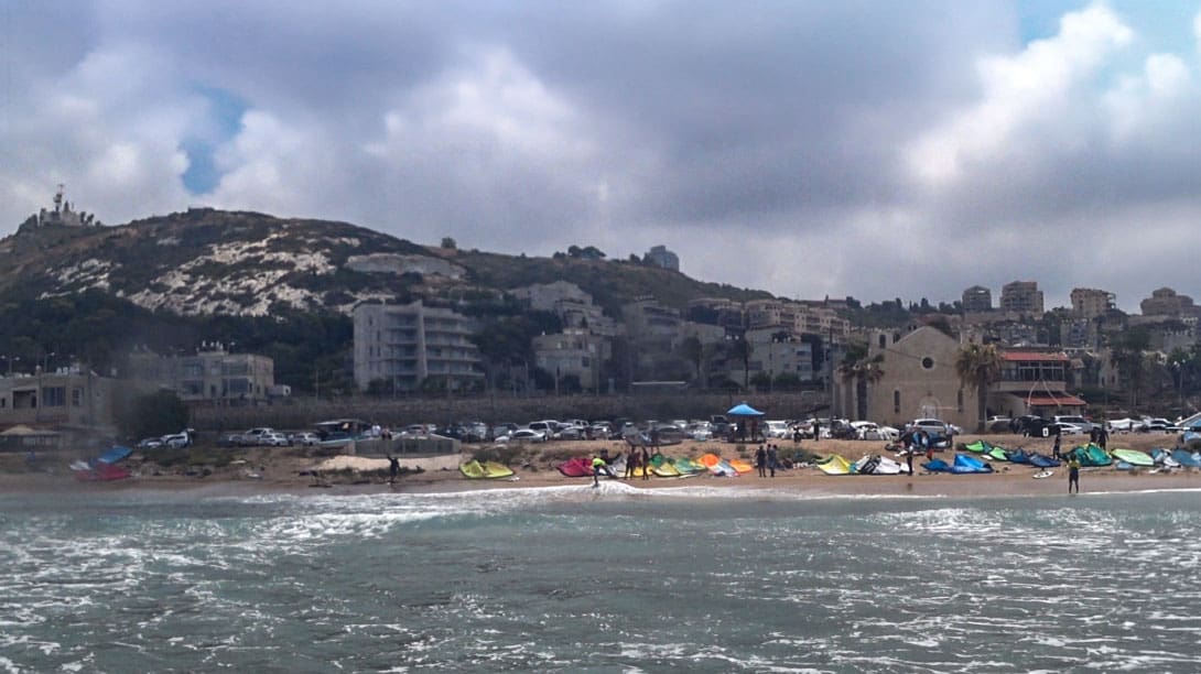 גולשים בחוף הכנסיה ומאחוריהם הענן השחור של הקיץ, המיטיב עם תושבי חיפה כשהוא עושה צל על הכרמל (צילום: ירון כרמי)