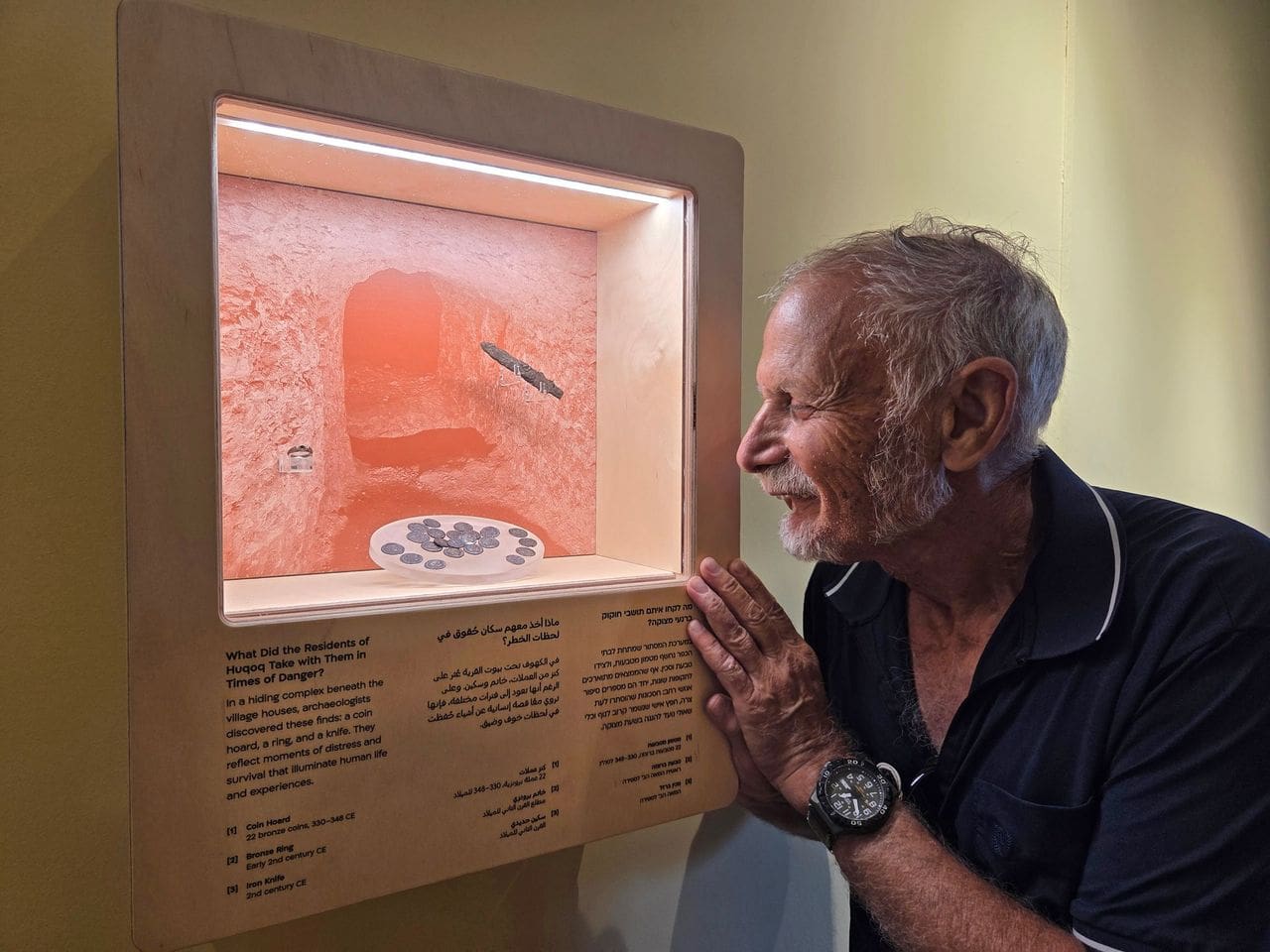 פרופ' ינון שבטיאל לצד מטמון מטבעות, סכין ברזל וטבעת ברונזה שהתגלו במכלול המסתור בחוקוק, במהלך חפירות של רשות העתיקות והמכללה האקדמית צפת. (צילום: עינת עמבר-ערמון, רשות העתיקות)
 