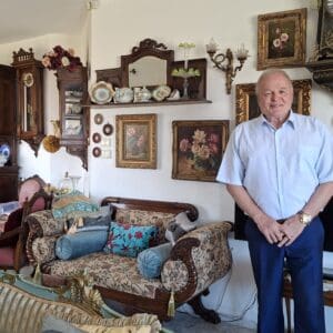 יונה מזור – בסלון מעונו, לצד הספה האהודה ואוספים עתיקים (צילום: רחלי אורבך)